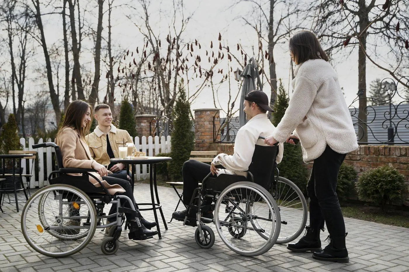 Friends, two using wheelchairs, meeting at an outdoor café