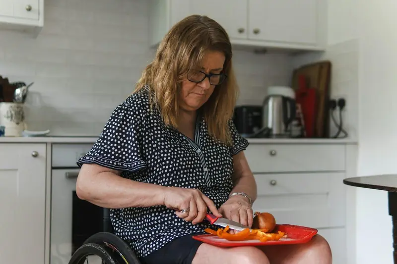 A woman using a wheelchair cooking in her kitchen