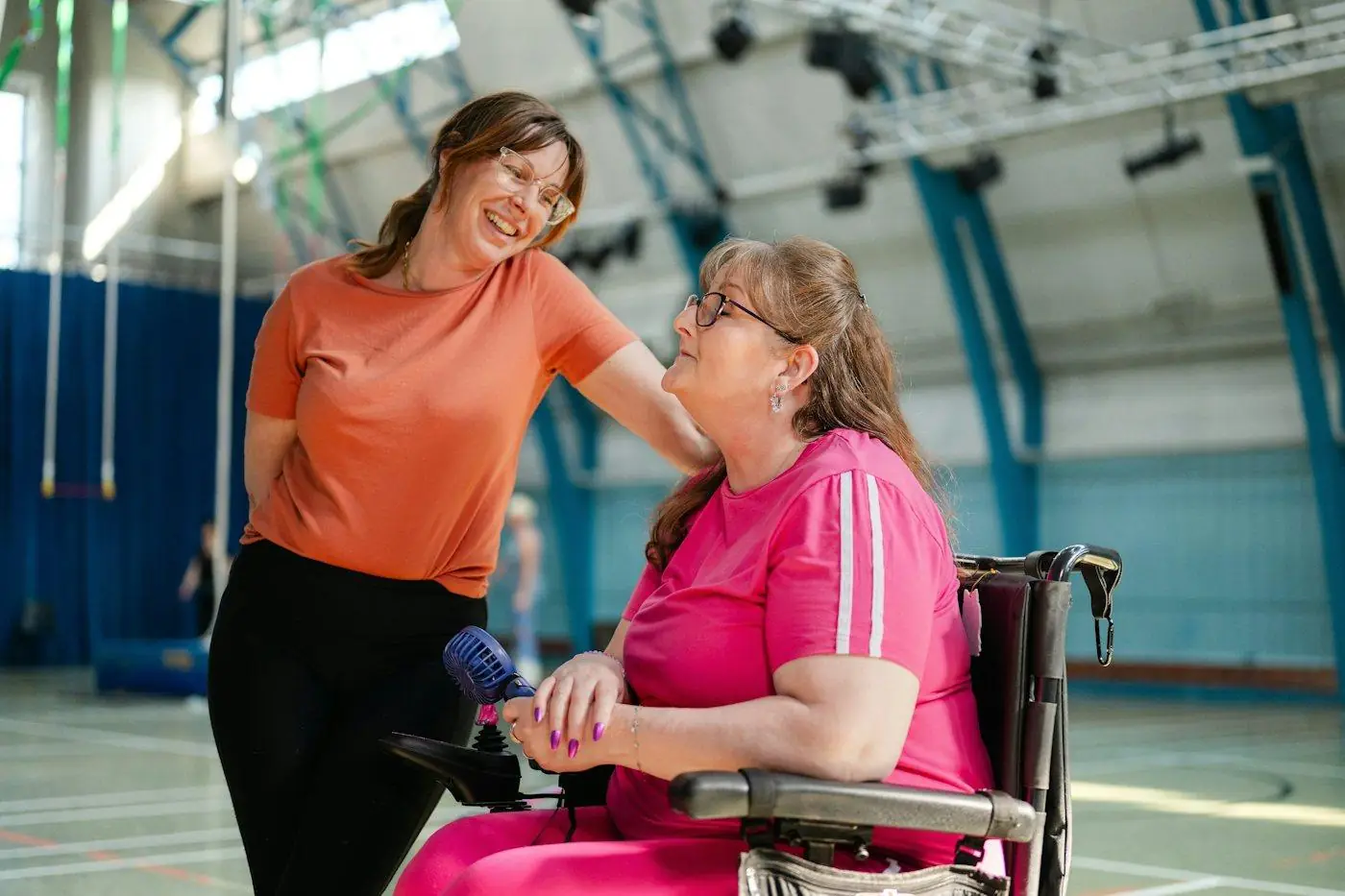 A support worker and a woman using a wheelchair laughing together
