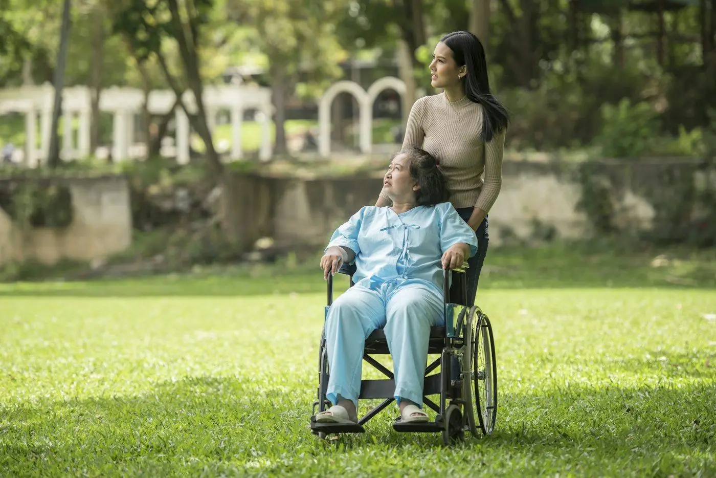 A support worker and a woman using a wheelchair enjoying a sunny park