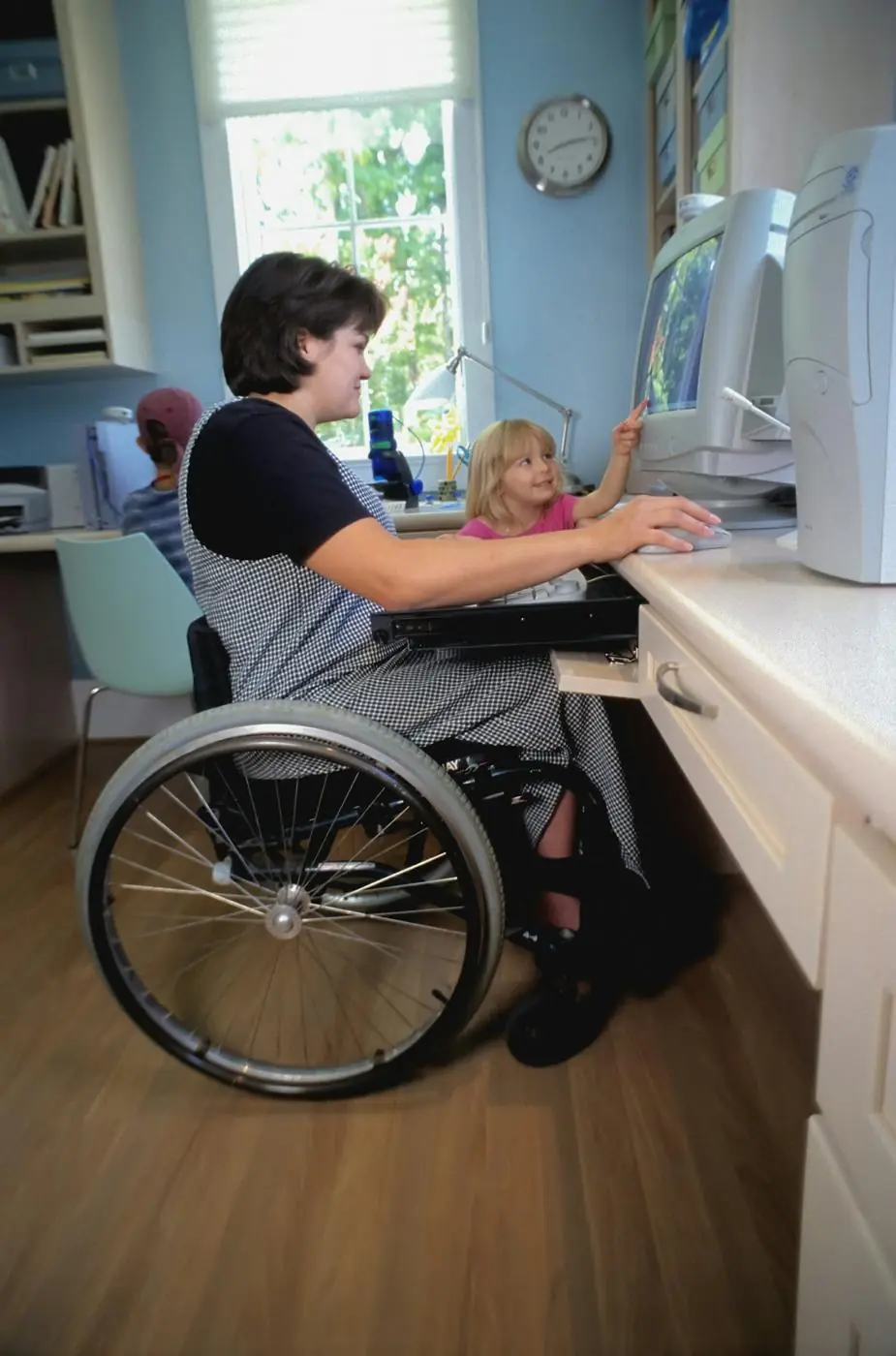 A woman using a wheelchair working at a computer desk